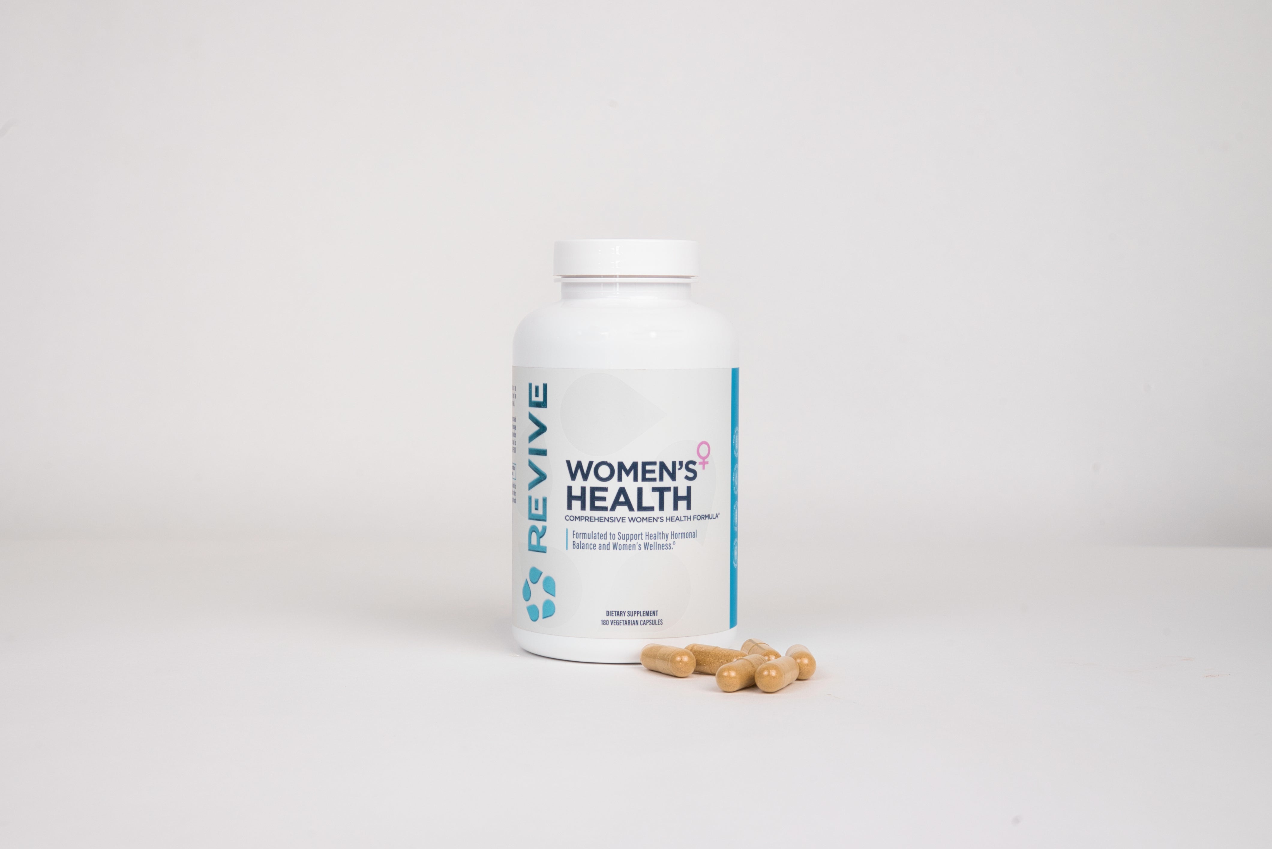 Woman smiling, holding a bottle labeled 'Women's Health' and a pill.