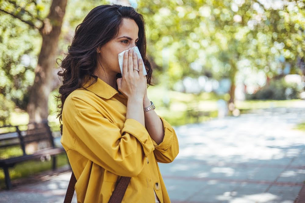 Brunette woman blowing her nose into a tissue